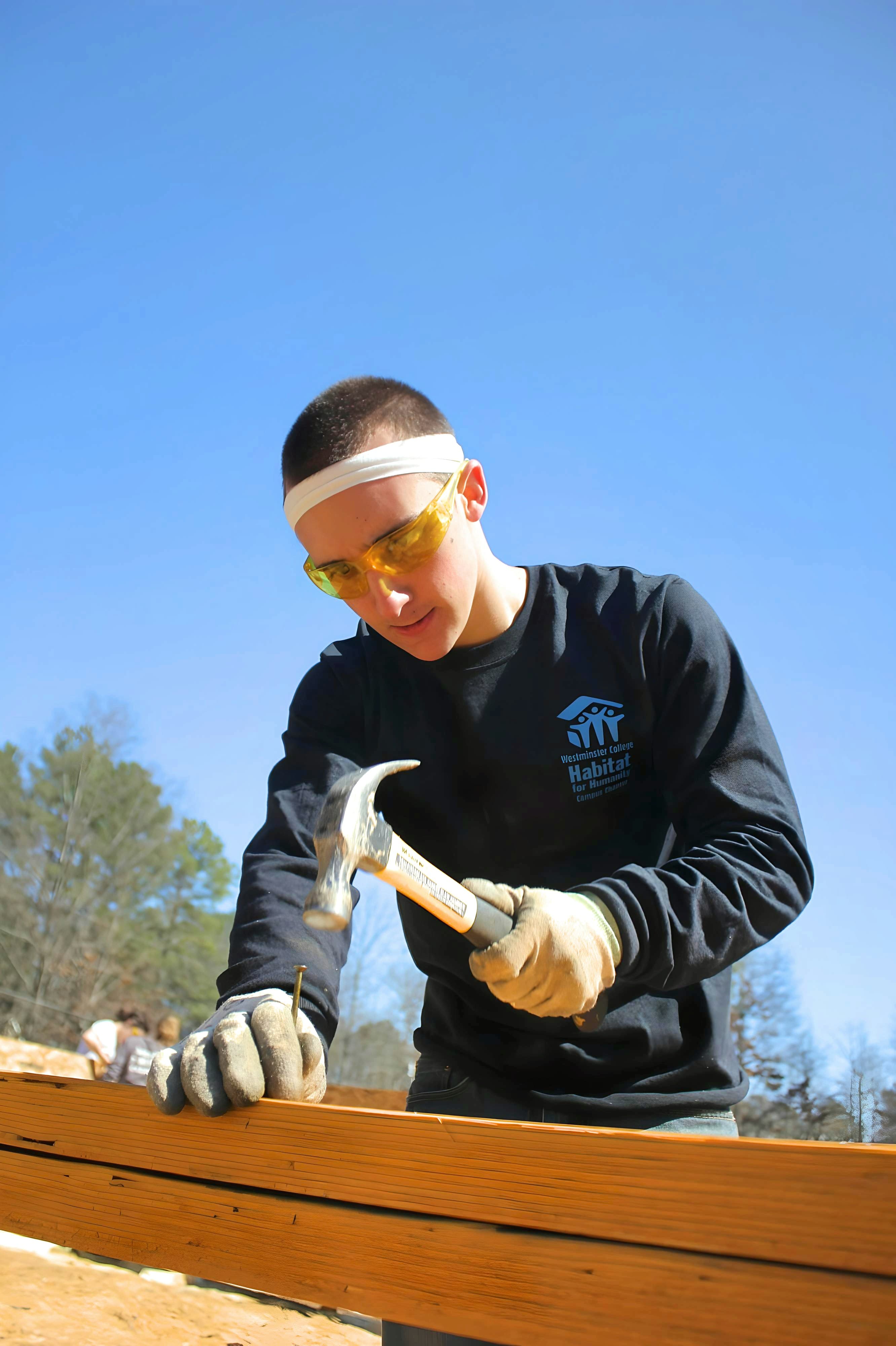 Volunteer hammering framing on a Habitat for Humanity build