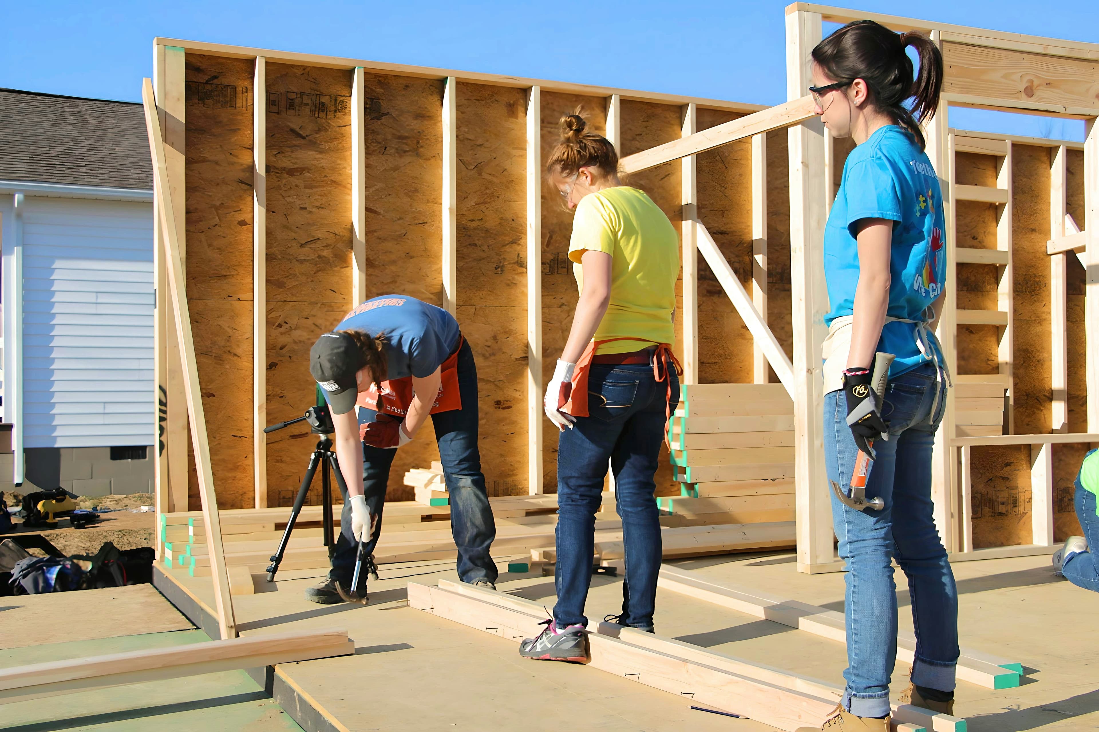 Volunteer crew raising a framed wall on a community build